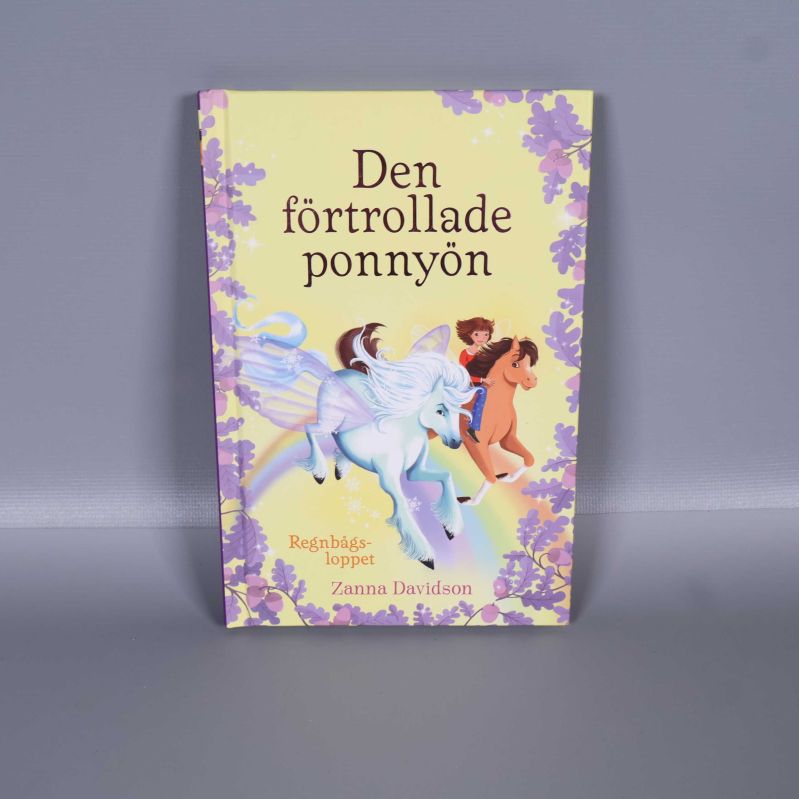 Framsidan av barnboken Den förtrollade ponnyön med färgglad illustration av ponnyer