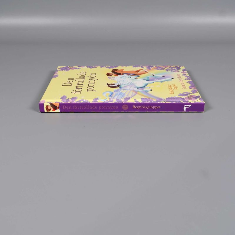 Boken Den förtrollade ponnyön placerad med ryggen synlig och lila detaljer