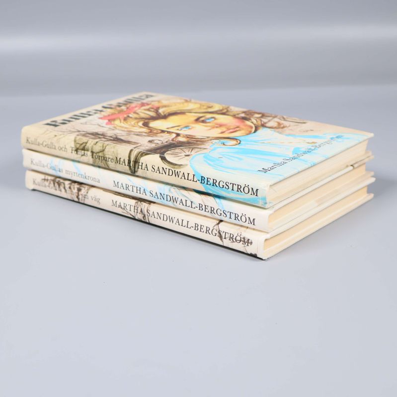 Kulla-Gulla böcker staplade på varandra, ryggarna synliga med titlar och författare