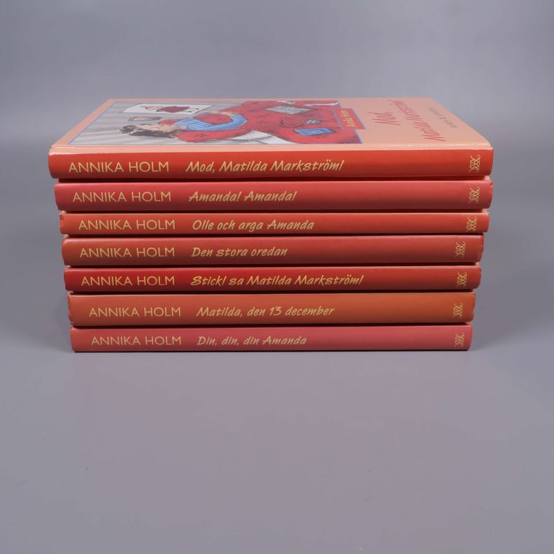 Boktravar på varandra med titlar av Annika Holm på bokryggarna