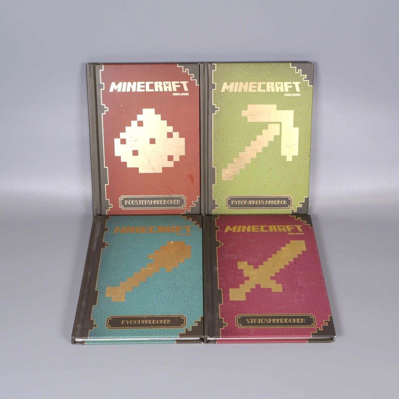 Fyra Minecraft-handböcker med pixlade guldmotiv på omslagen