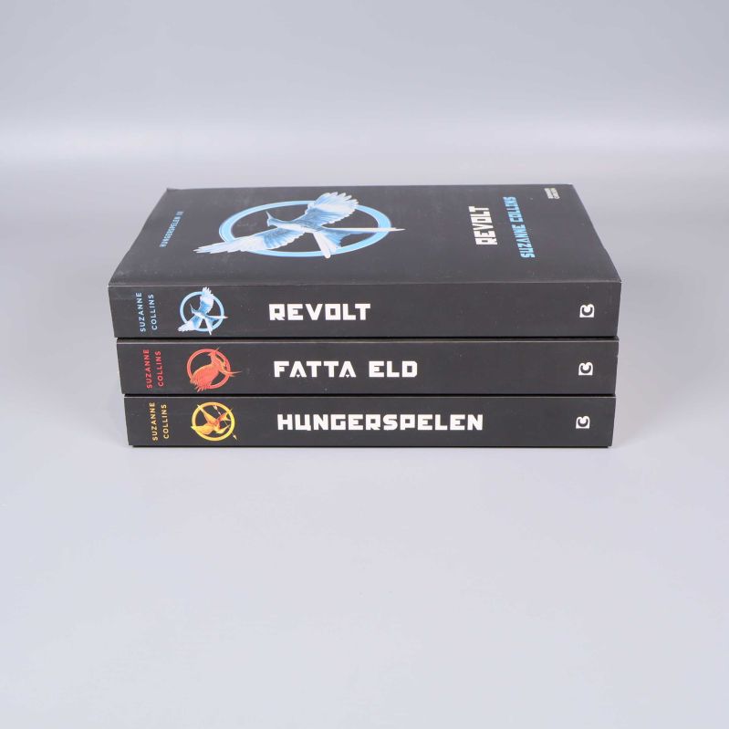 Trilogins böcker staplade med titlar på ryggarna