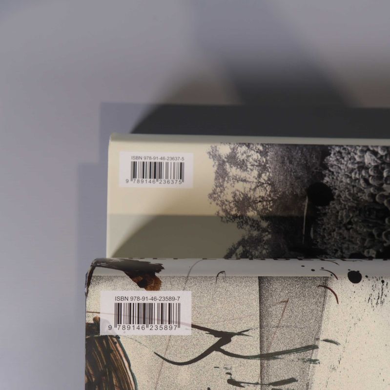 Två böcker med ISBN-etiketter på baksidan, barcode och nummer synliga