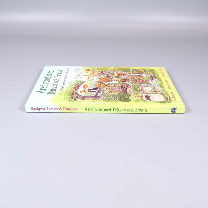 Boken Året runt med Pettson och Findus liggande på sidan, ryggen synlig