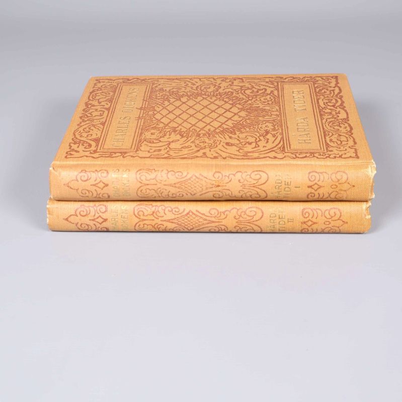 Två böcker staplade, visar rygg med titlar och dekor