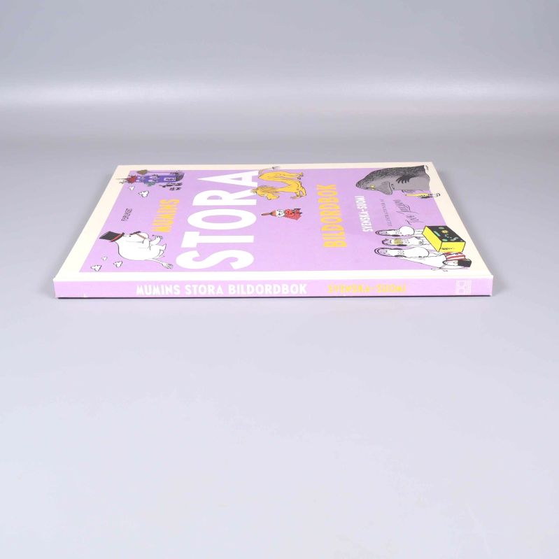 Mumins stora bildordbok visad från sidan mot den lila ryggen