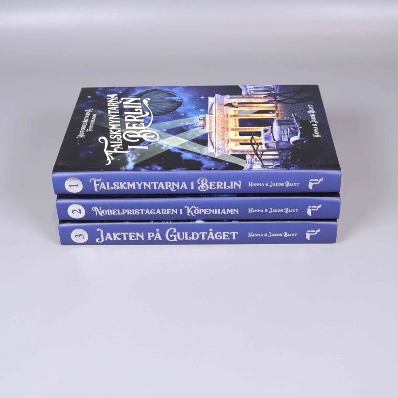 Ryggar på tre böcker med titlar och numrering