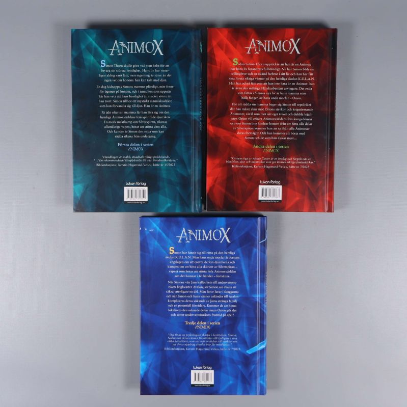 Baksidor av tre Animox-böcker med text och streckkoder