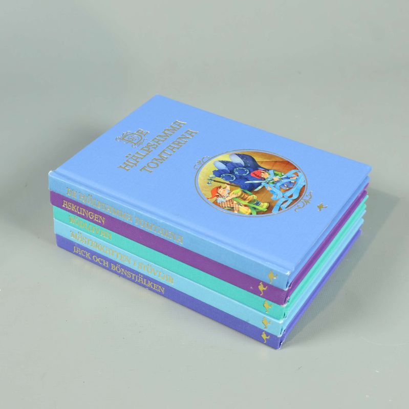 Fem hårdbandsböcker ur Sagobiblioteket staplade, färgade omslag synliga
