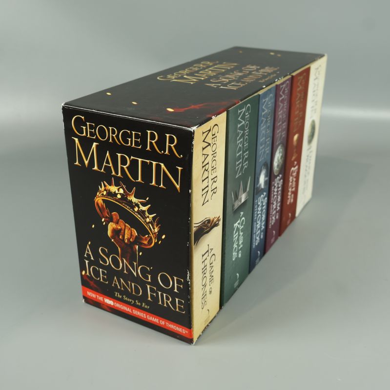 Bokbox med sju böcker av George R.R. Martin med detaljerad framsida och titlar