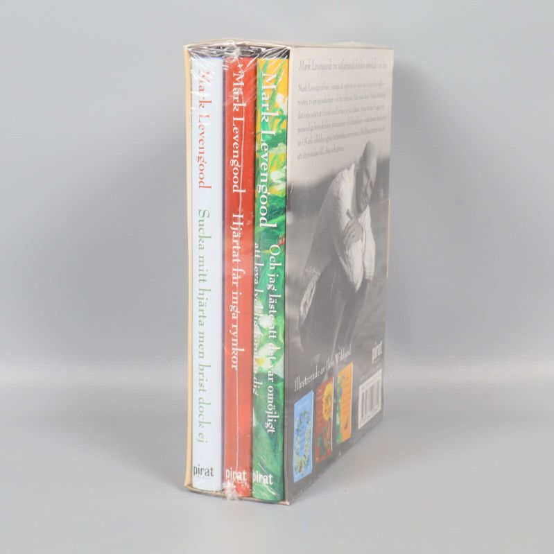 Tre inplastade böcker i samlingsbox, visar titlar och färgglada ryggar