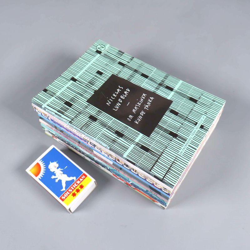 Novellsamling i pocketformat staplade bredvid tändsticksask