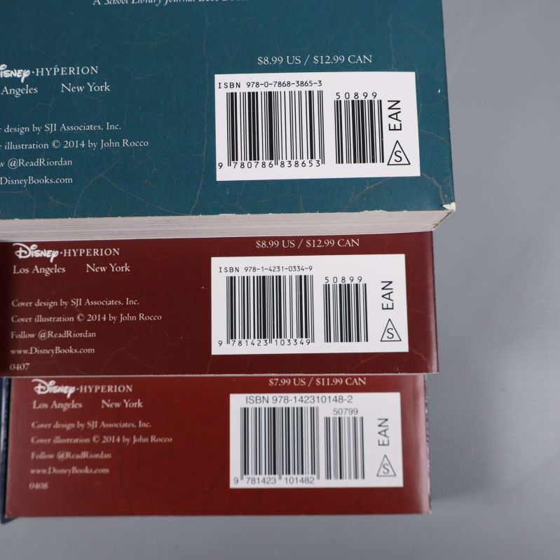 Närbild på tre bokryggar med ISBN-nummer, streckkoder och förlagsinformation