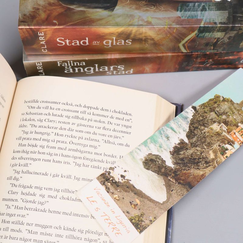 Uppslagen bok med svensk text och bokmärke bredvid två bokryggar