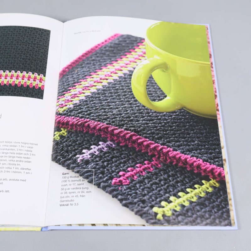 Interiörbild ur boken med virkat underlägg och mugg i fokus