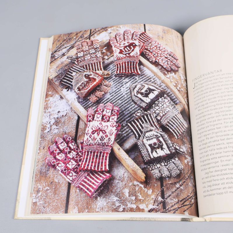 Flerfärgade stickade vantar och handskar upplagda på planka i boken