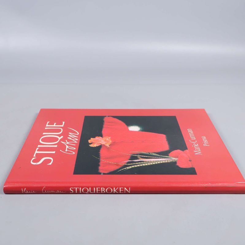 Stiqueboken sedd från sidan med tydlig ryggtext och författarnamn