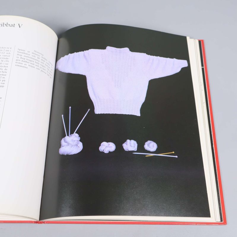 Foto på uppslag med stickat plagg och garnnystan i vitt