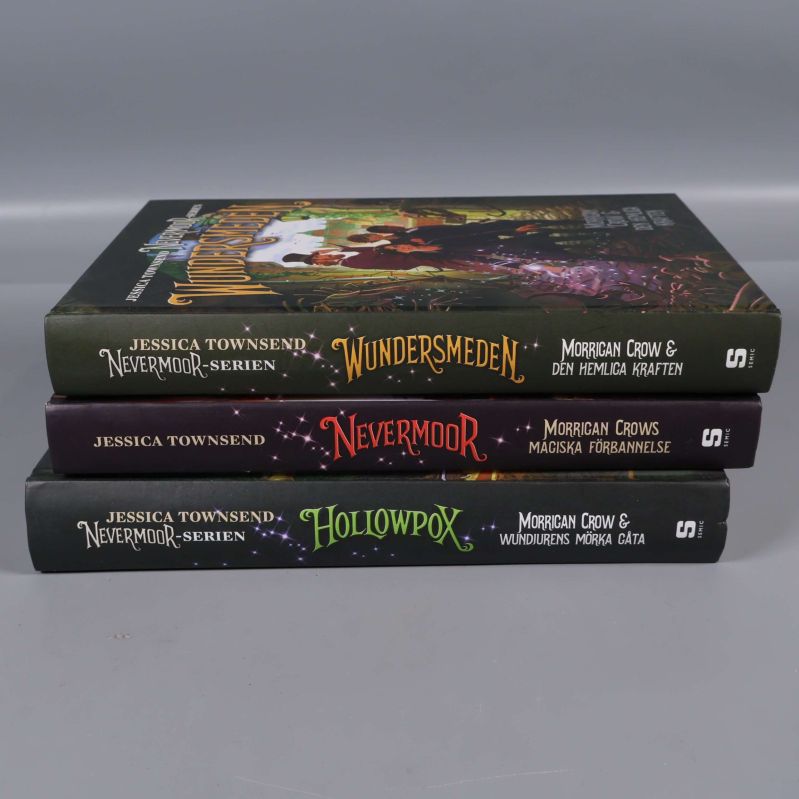 Ryggarna på Nevermoor-böckerna staplade i en hög