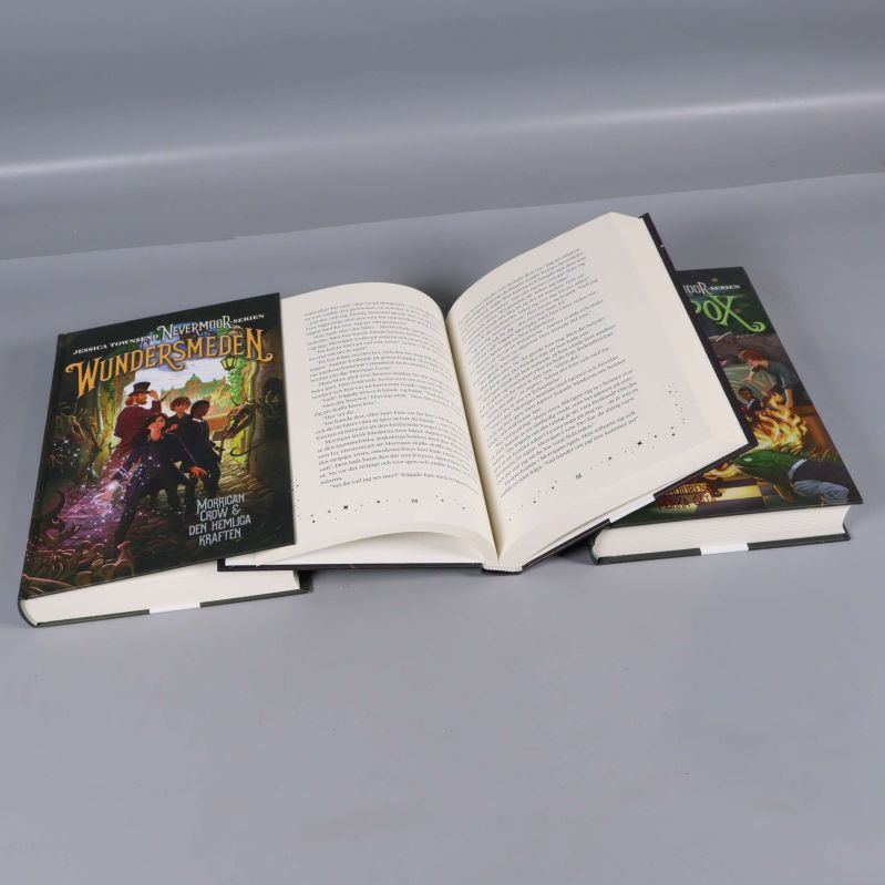 Öppna böcker ur Nevermoor-serien med synlig text