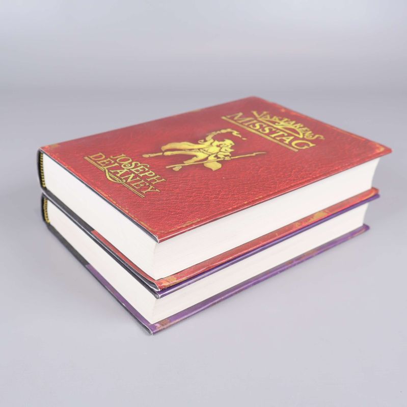 Två böcker staplade med tydligt fokus på övre bokens omslag