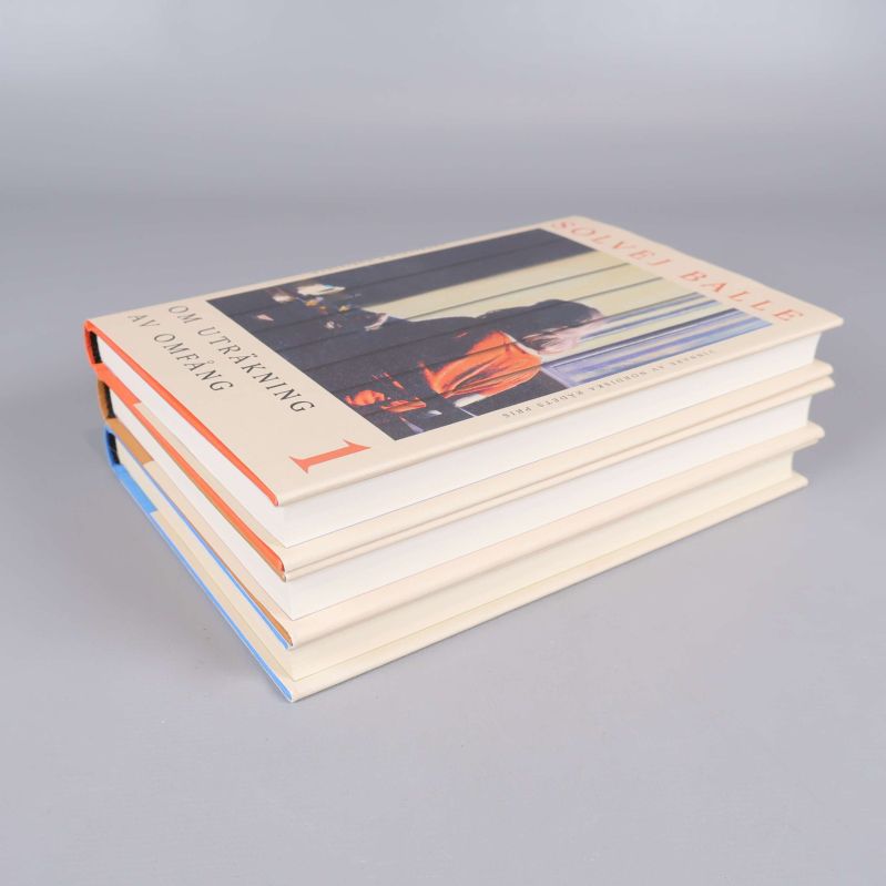 Närbild på tre staplade böcker med synliga omslag och färgade kanter