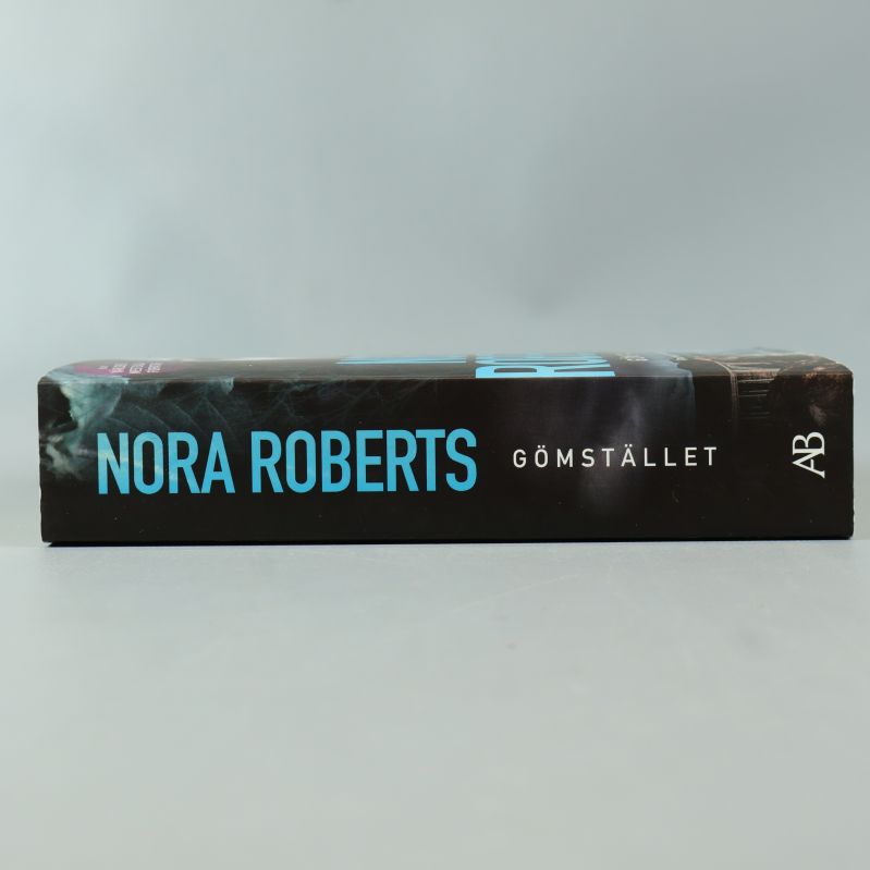 Bokrygg med Nora Roberts och Gömstället i blå text