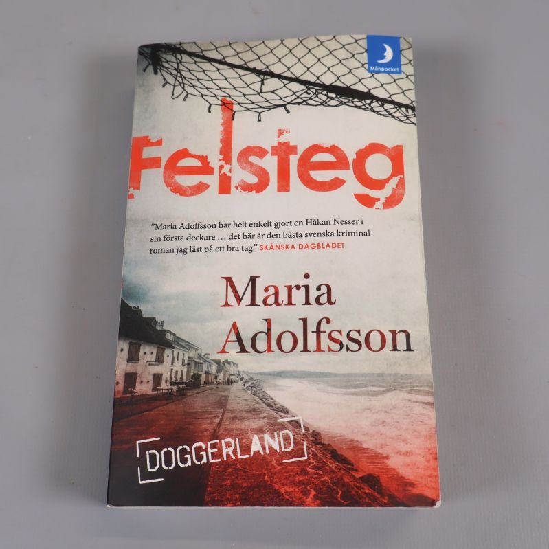 Framsidan av pocketboken Felsteg av Maria Adolfsson med röd titeltext och kustmotiv