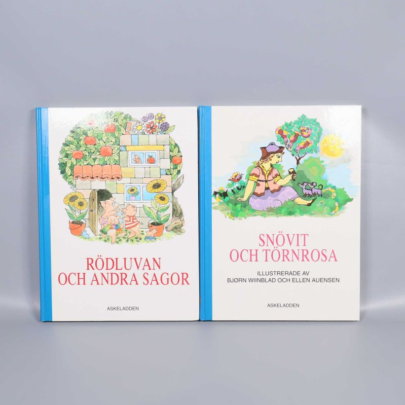 Två sagoböcker med blå ryggar och färgglada omslag