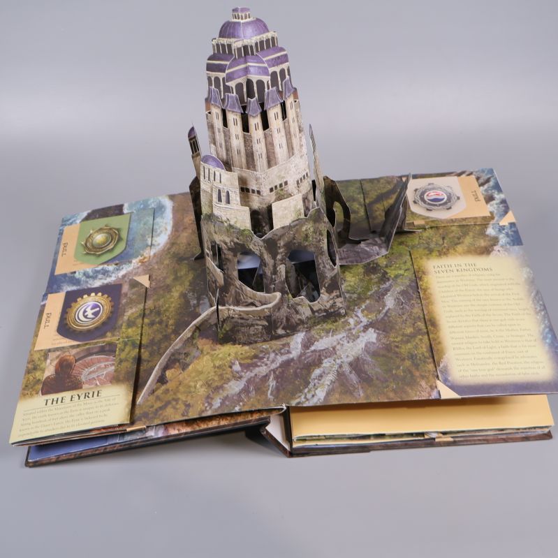 Uppslagen pop up-sida i Game of Thrones-bok med illustration av fästning