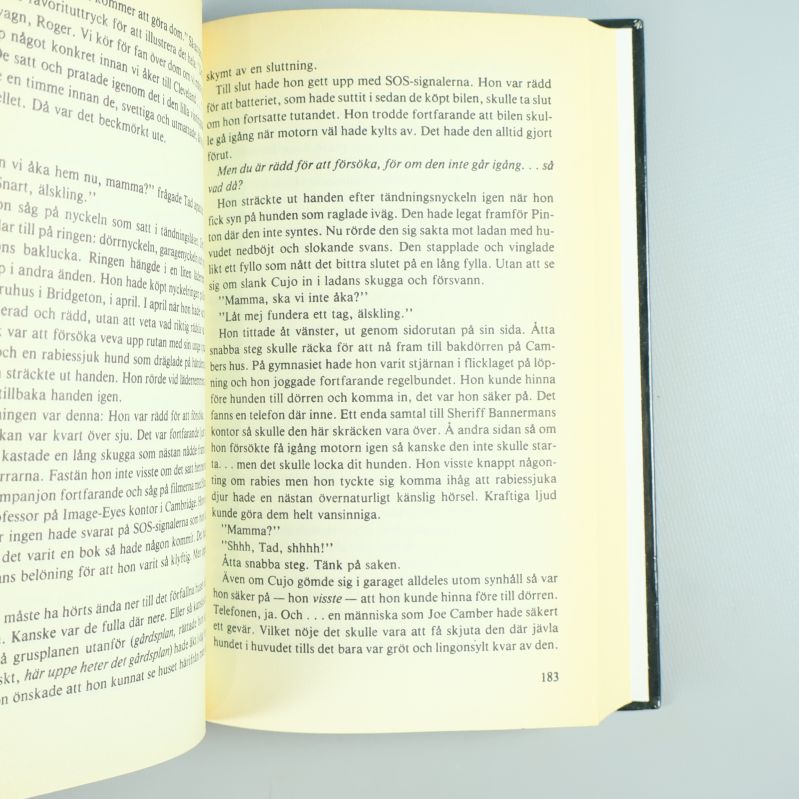 Närbild av ett uppslag i Cujo med svensk text på sidorna