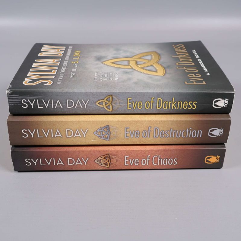 Ryggar av tre böcker från Sylvia Days Marked-serie, med titlar och symbol i kontrasterande färger.