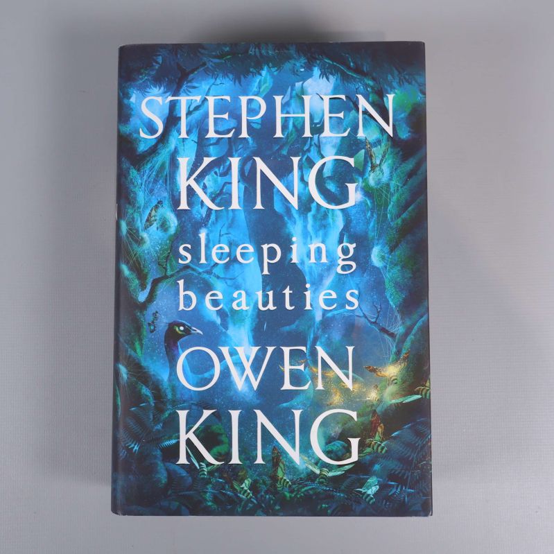 Omslag av boken Sleeping beauties av Stephen och Owen King, blått skogsmotiv