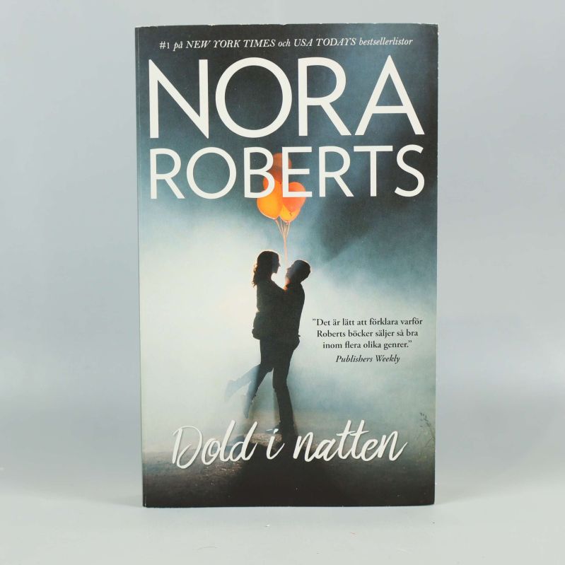 Framsidan av romanen Dold i natten av Nora Roberts med silhuetter och ballonger