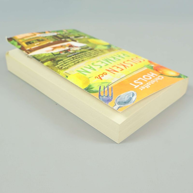 Boken Solsken och parmesan liggande, visar bokpärmens och sidornas tjocklek