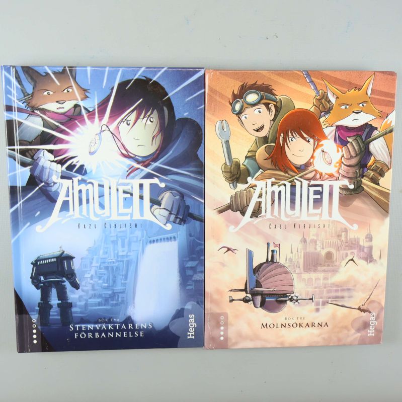 Två böcker ur Amulett-serien, omslag med färgstarka illustrationer