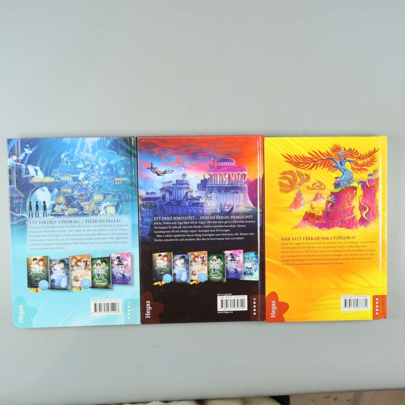 Baksidor av tre Amulett-böcker med beskrivningstext och illustrationer