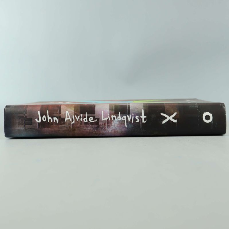 Bokrygg med texten John Ajvide Lindqvist och X-symbol