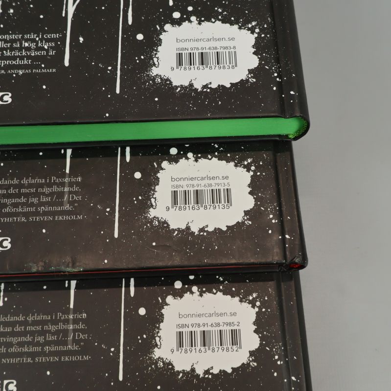 Närbild på ISBN-etiketter på baksidan av tre Pax-böcker
