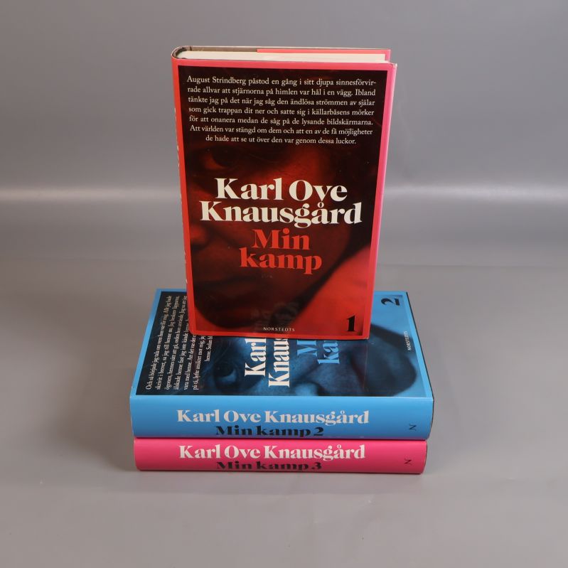 Tre böcker staplade med Min kamp 1 överst, röda, blå och rosa omslag