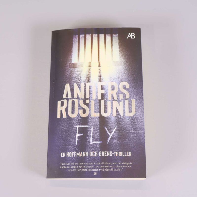 Framsidan av Fly av Anders Roslund med ljus genom fängelsegaller