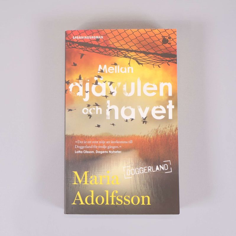 Framsidan av Mellan djävulen och havet med gult och orange omslag