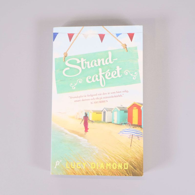 Framsidan av boken Strandcaféet med strandmotiv och färgglada strandhus