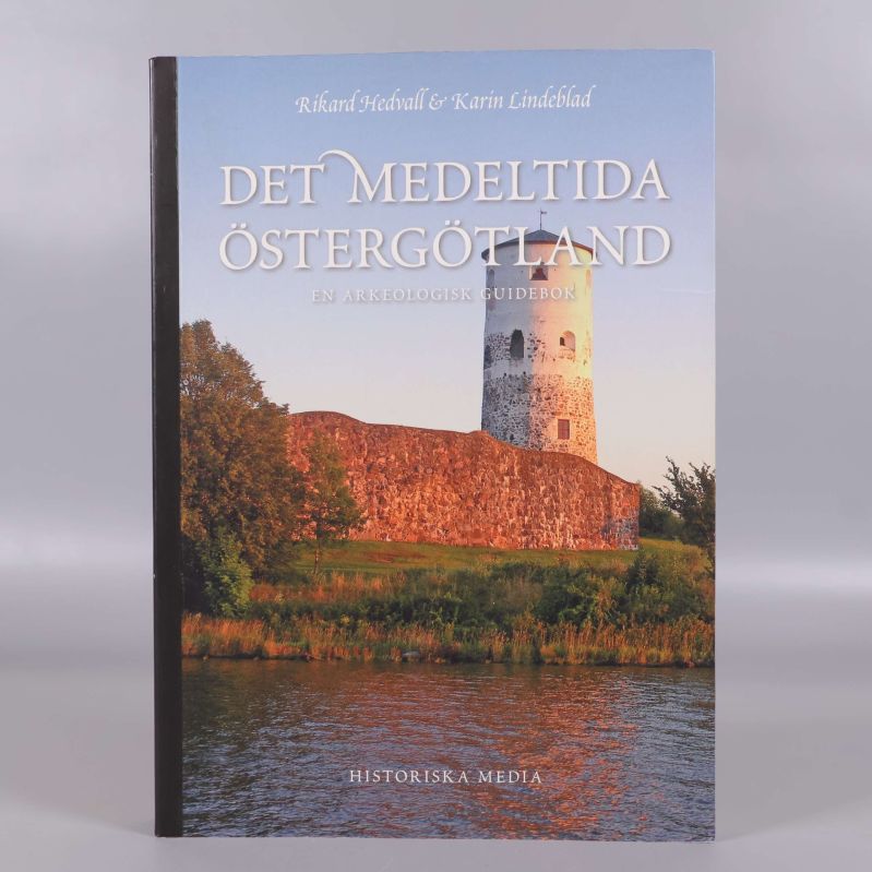 Framsidan av boken Det medeltida Östergötland med borg i solnedgång