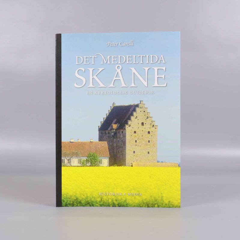 Framsidan av boken Det medeltida Skåne med borg och gul blomsteräng