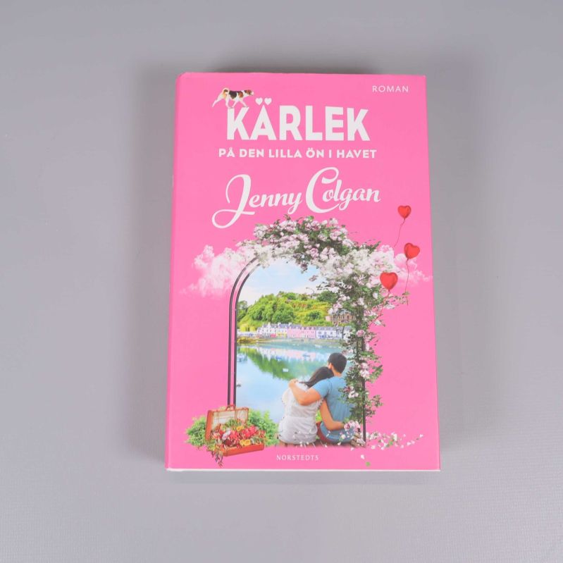 Framsidan av boken Kärlek på den lilla ön i havet med rosa omslag och illustration av ett par vid vattnet