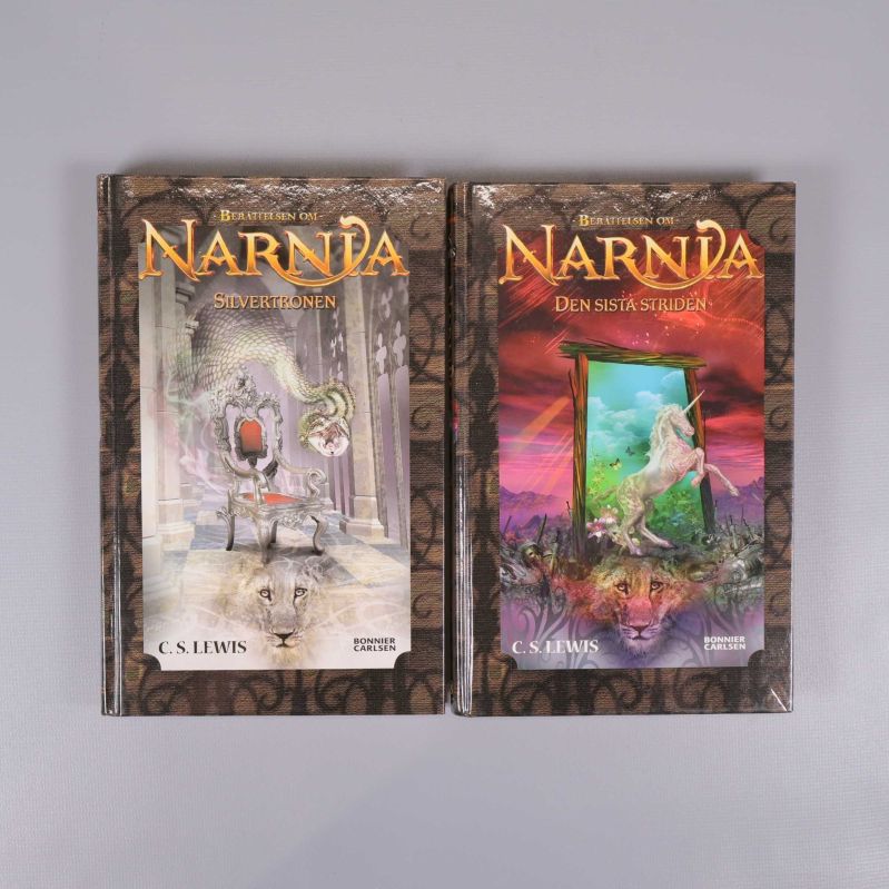 Två inbundna böcker ur serien Berättelsen om Narnia med illustrerade omslag