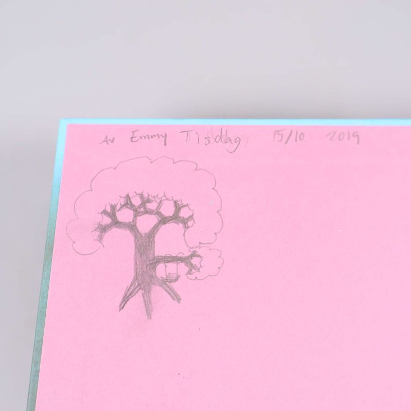 Handritad teckning och text på ett rosa papper i en bok