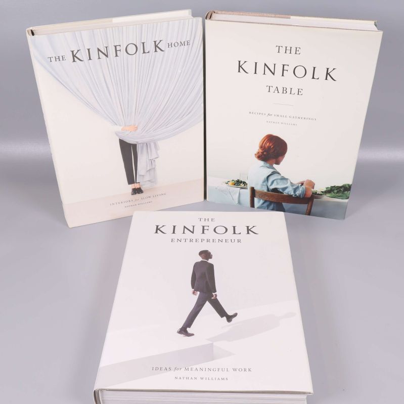 Framsidor på tre Kinfolk-böcker: Home, Table och Entrepreneur, stående mot grå bakgrund
