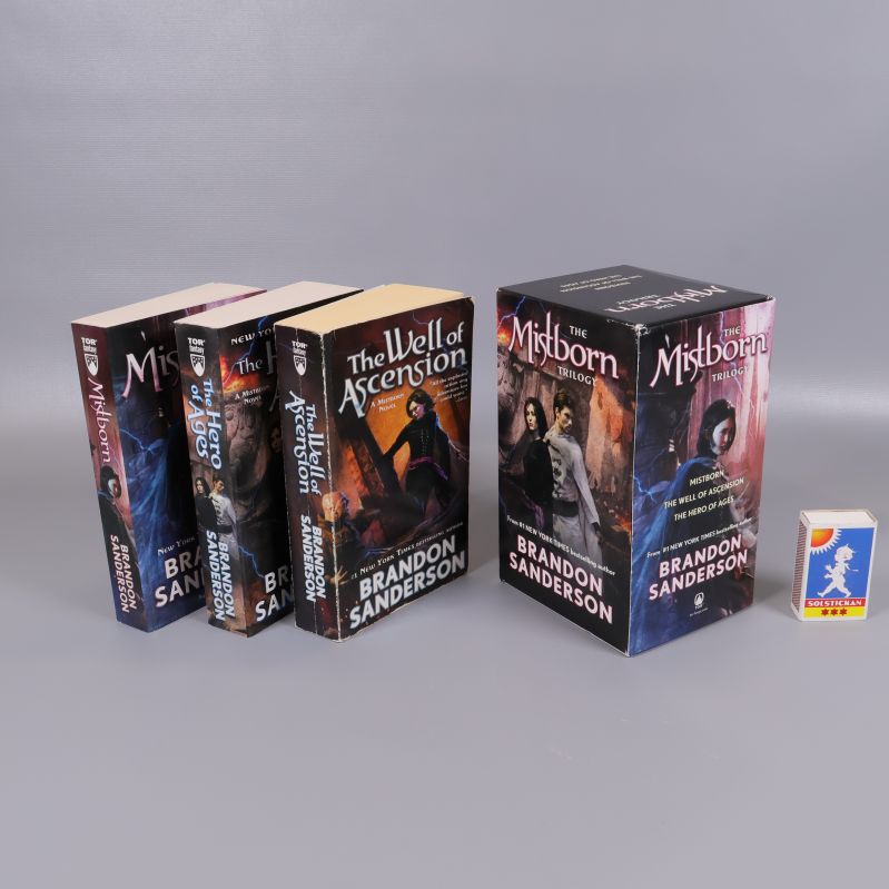 Alla tre böckerna ur Mistborn Trilogy och förpackning bredvid en tändsticksask